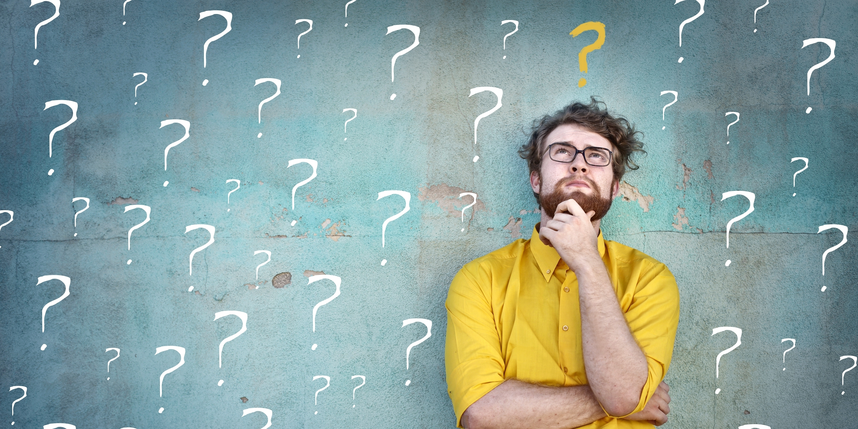 Young man in a yellow shirt against a blue background covered in white question marks